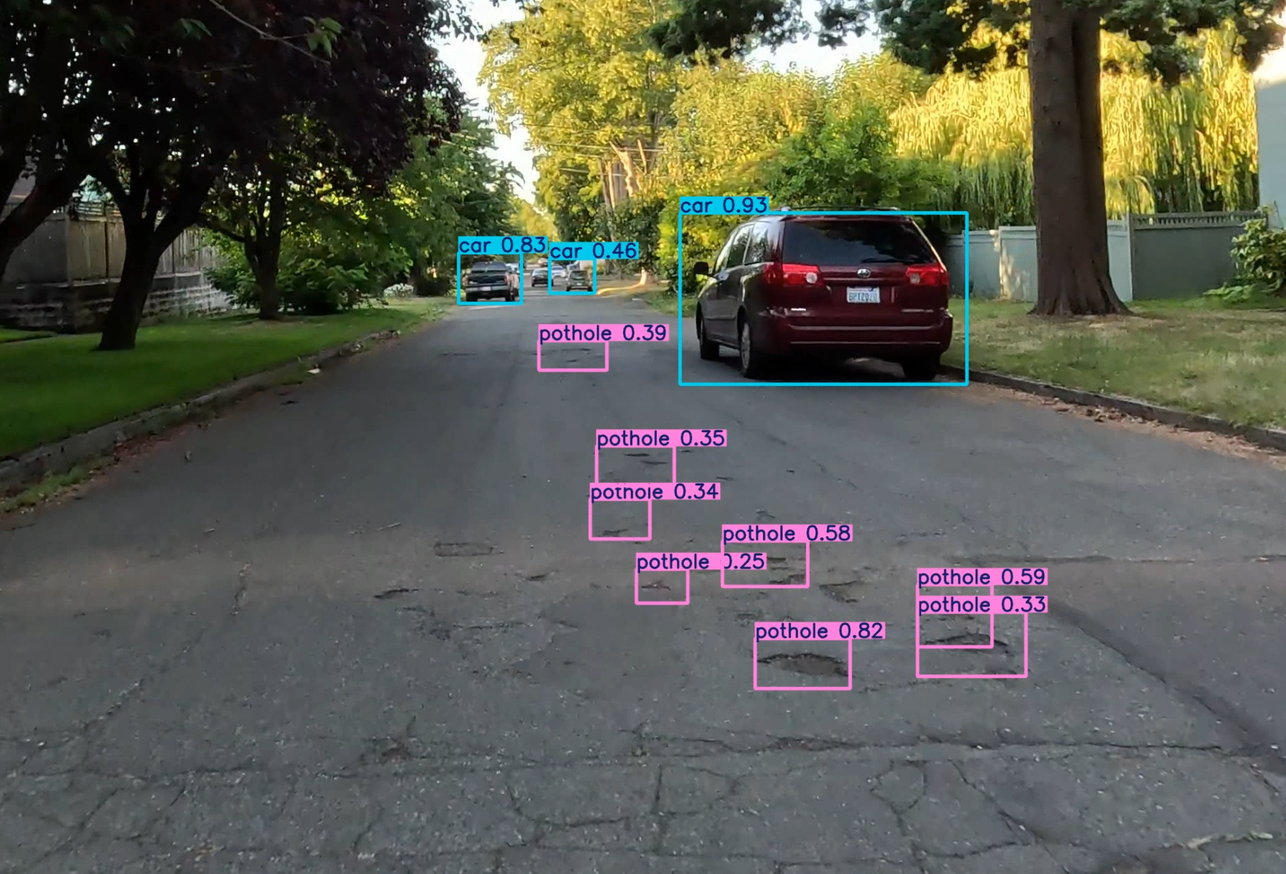 The image shows a pothole ridden street in the North End of Tacoma with colored rectangular outlines of the objects such as cars (blue) and potholes (purple).